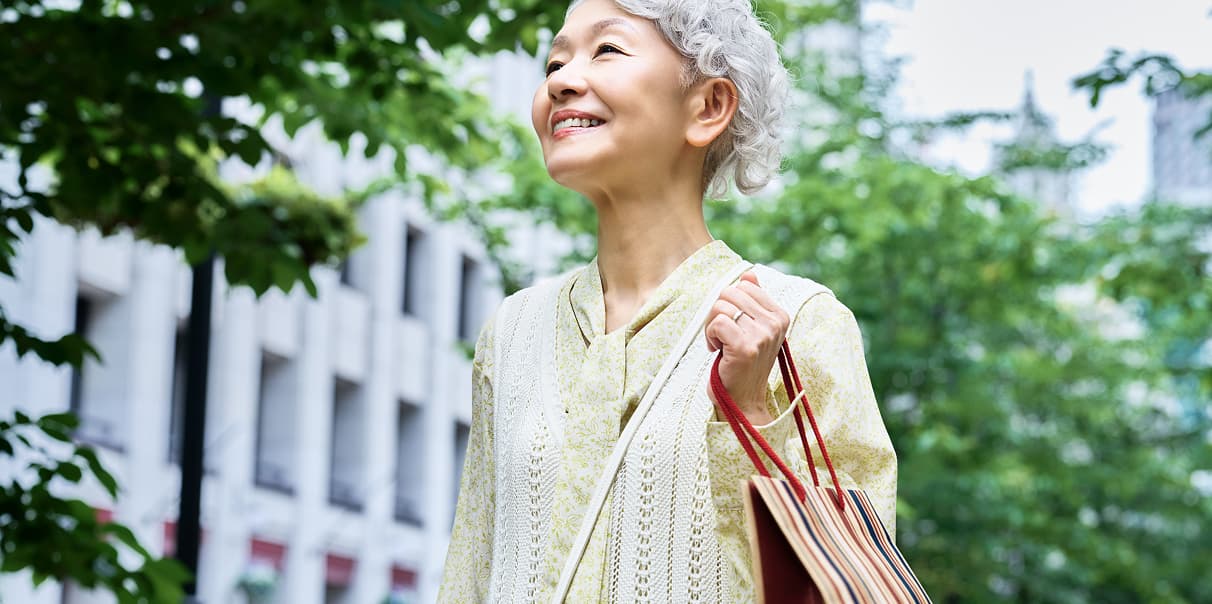 買い物袋を持って歩く年配の女性